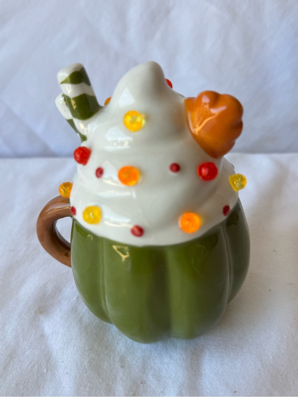 Pumpkin Mug Light Up Decor featuring white whipped cream topping and a green-and